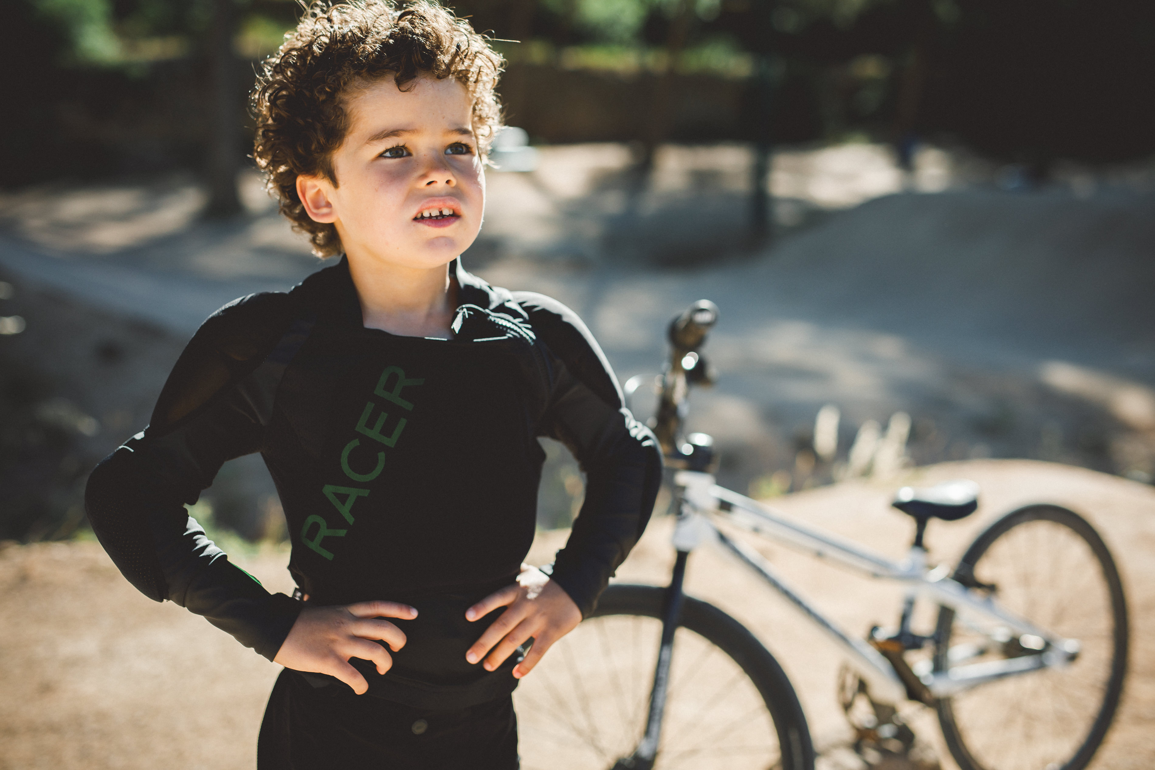 Enfant &eacute;quip&eacute; de protections VTT compl&egrave;tes sur un sentier de montagne